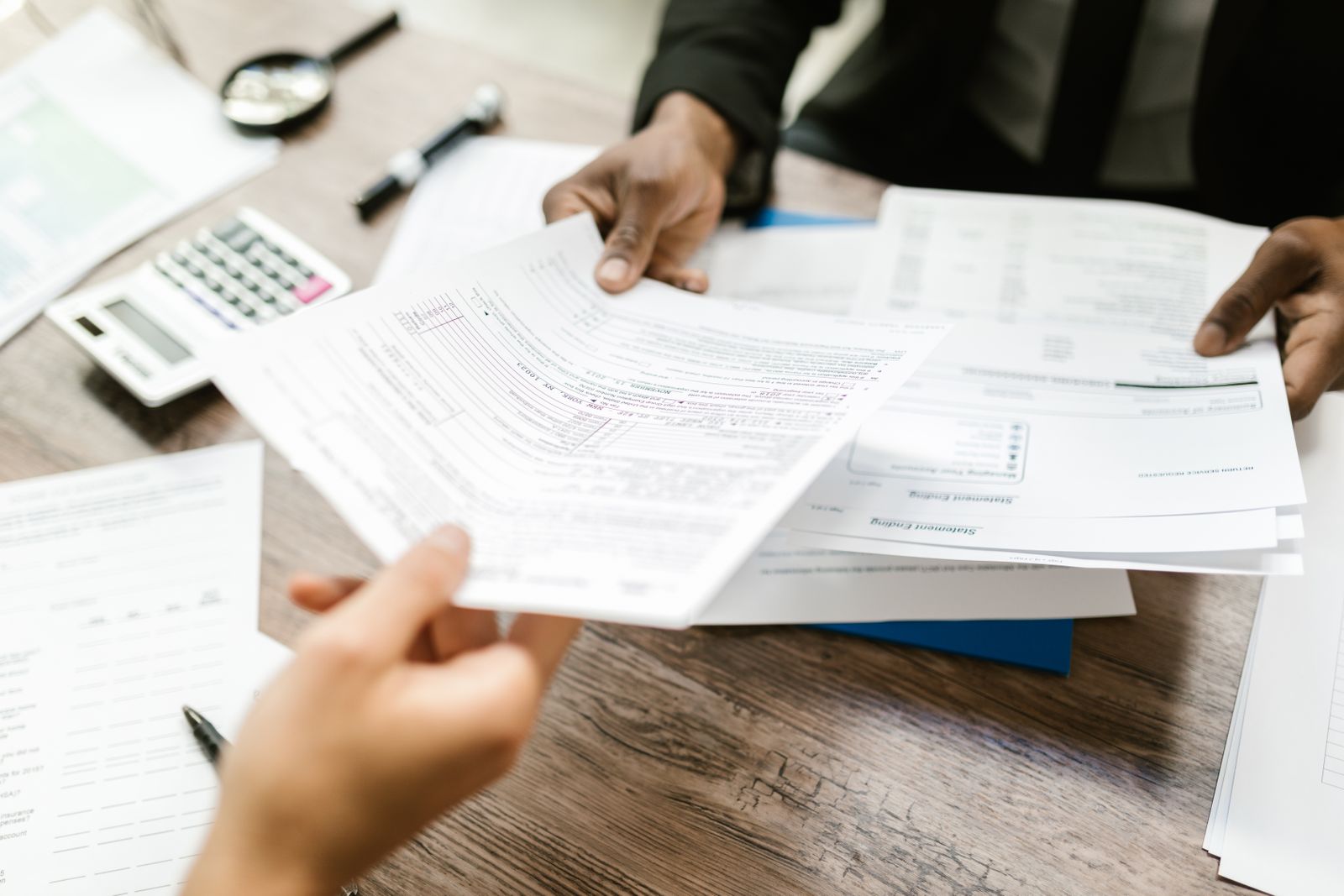 Two people handing documents across a desk during a handover