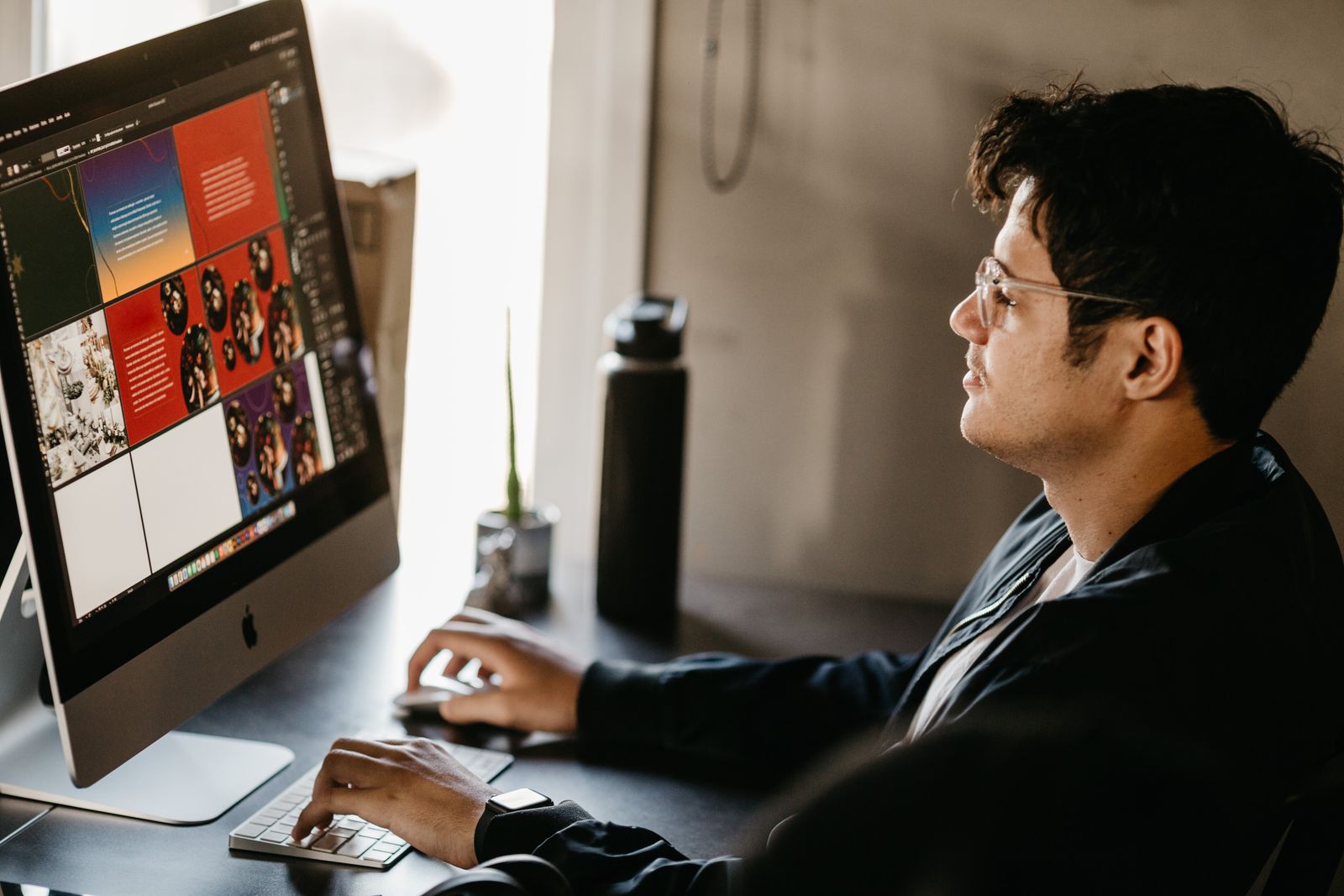 A designer at a desktop computer reviewing a grid of page layouts