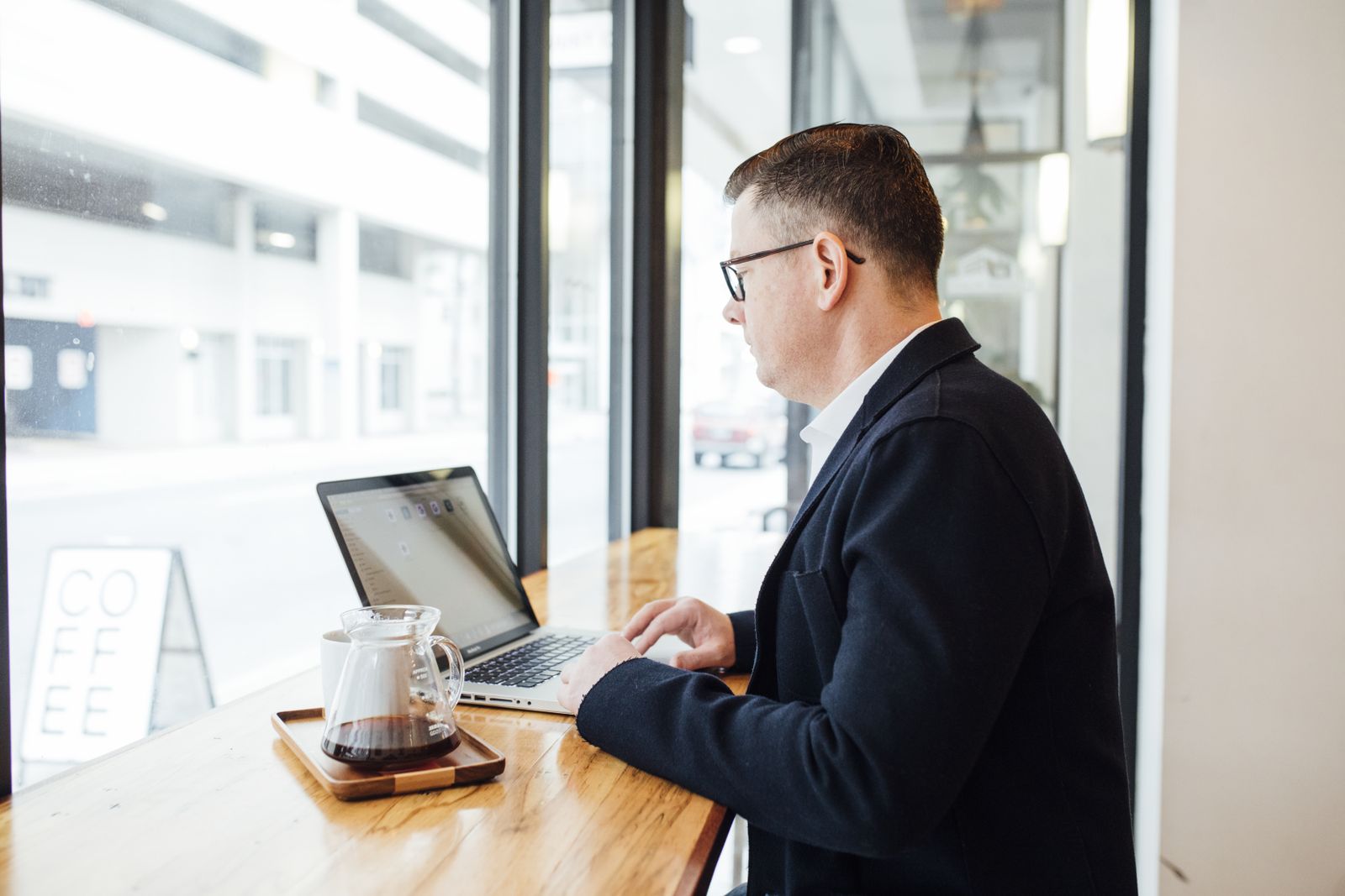 A marketing freelancer working on a laptop at a cafe counter