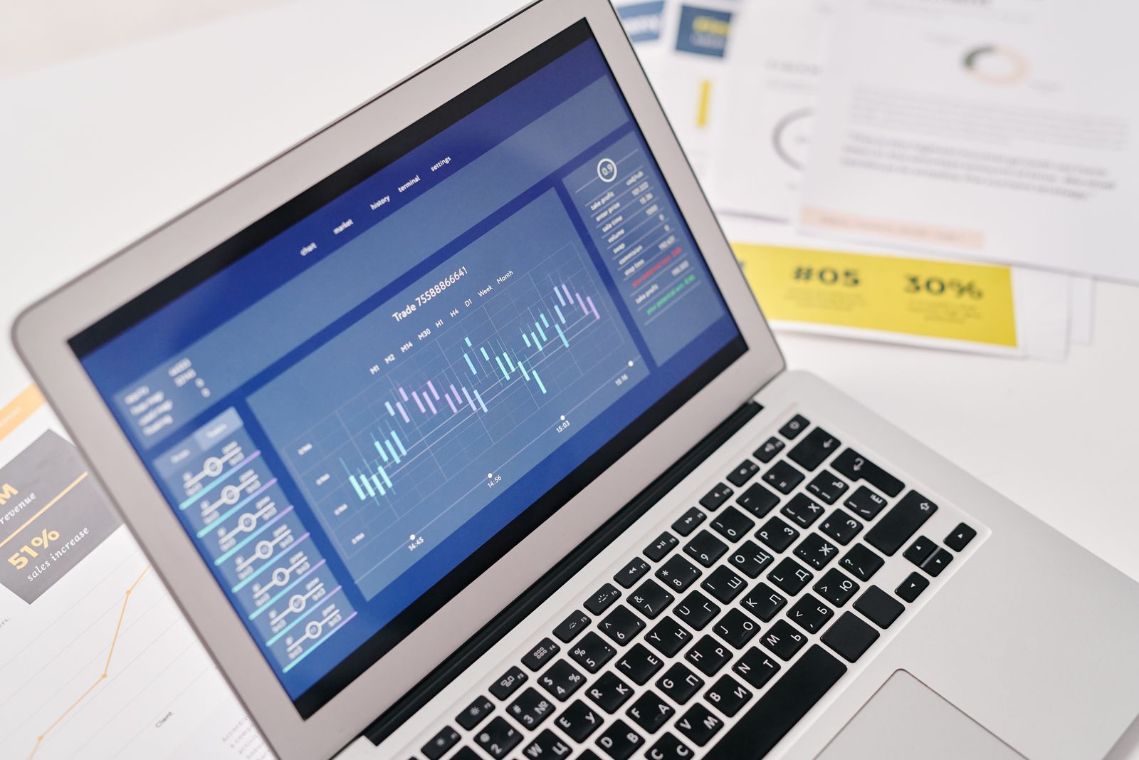 A laptop showing an advertising performance dashboard next to printed campaign reports