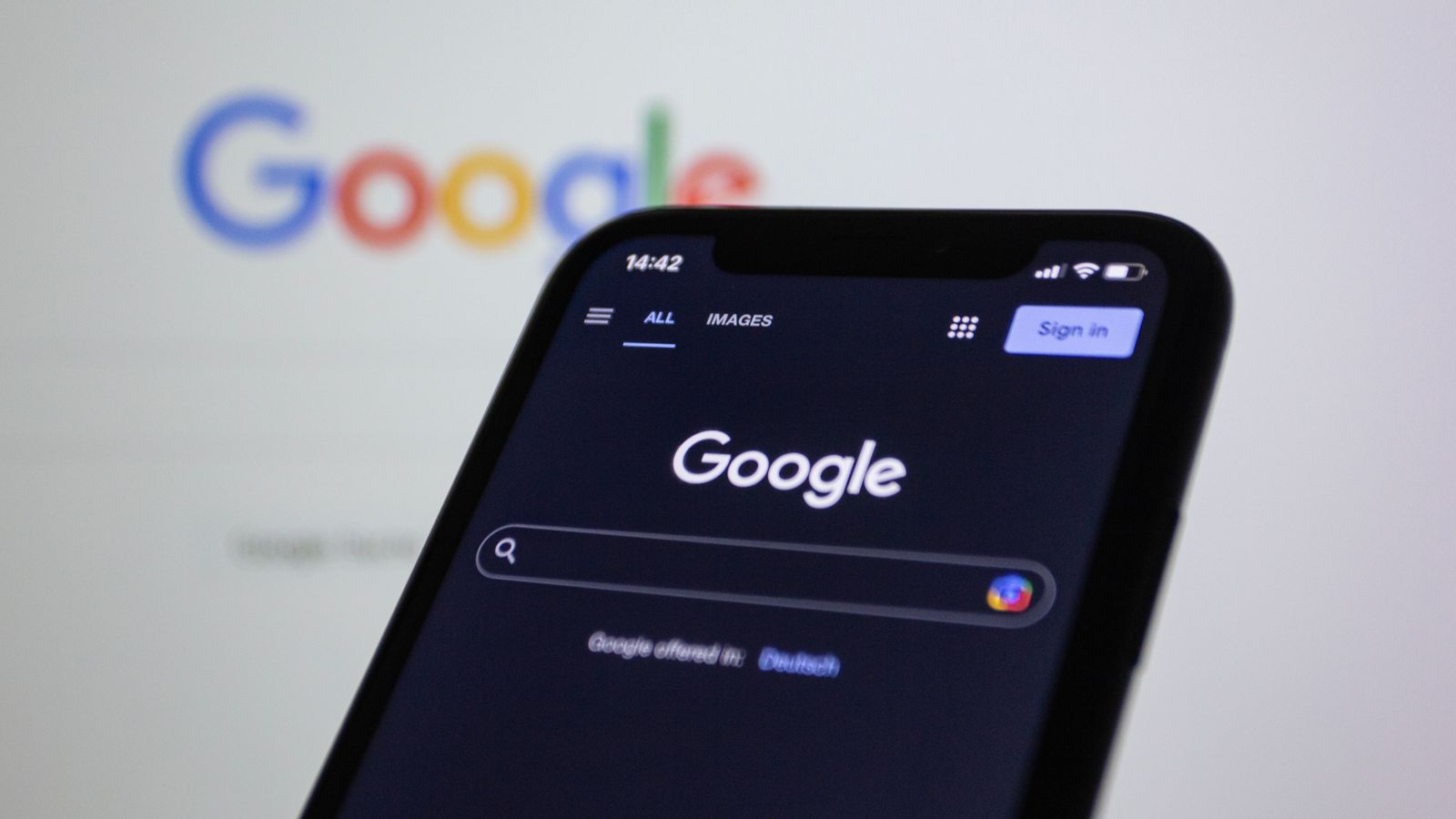 A smartphone showing a search engine home page held in front of a screen
