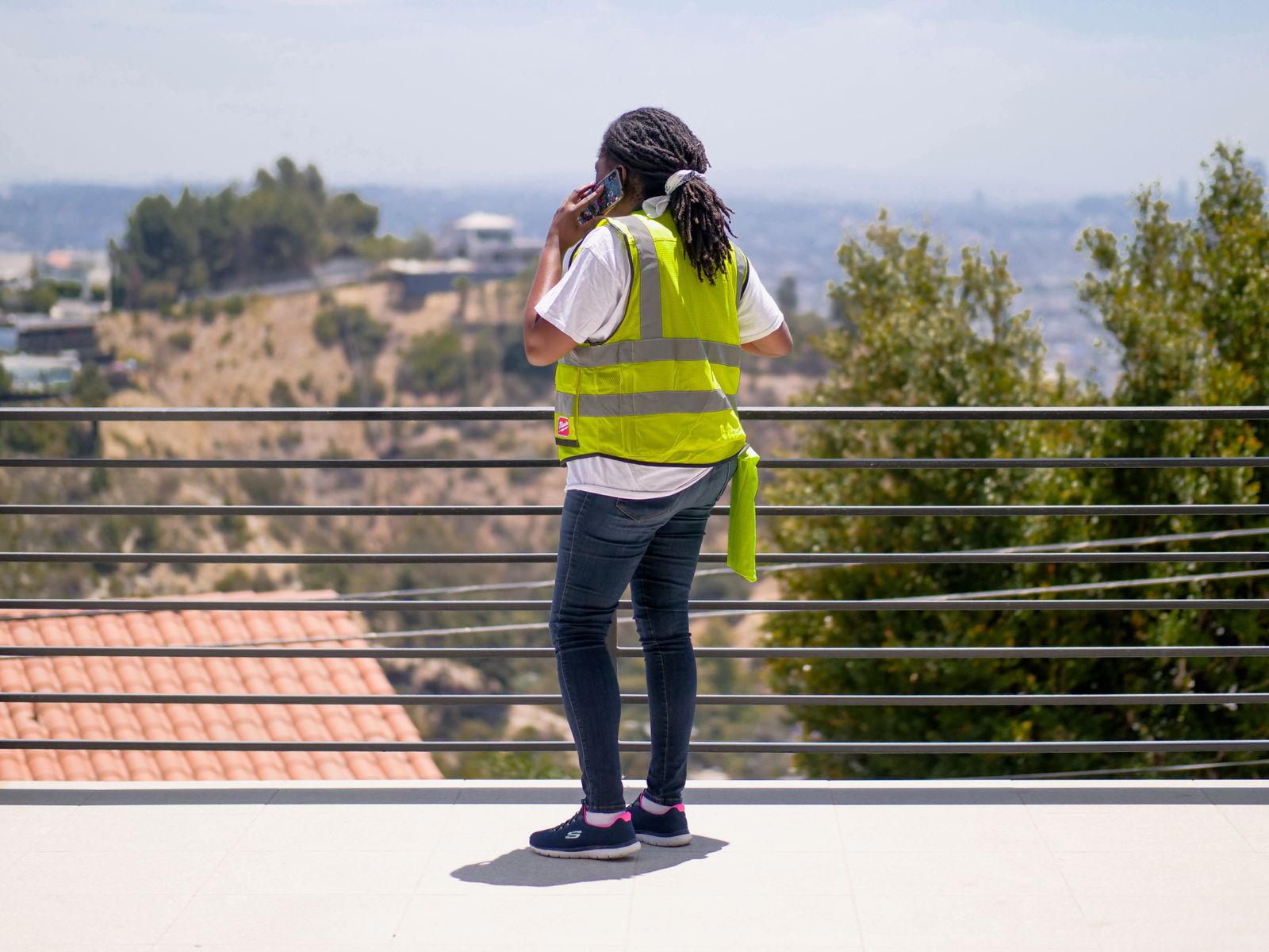 A service technician in a hi-vis vest taking a call outside a property