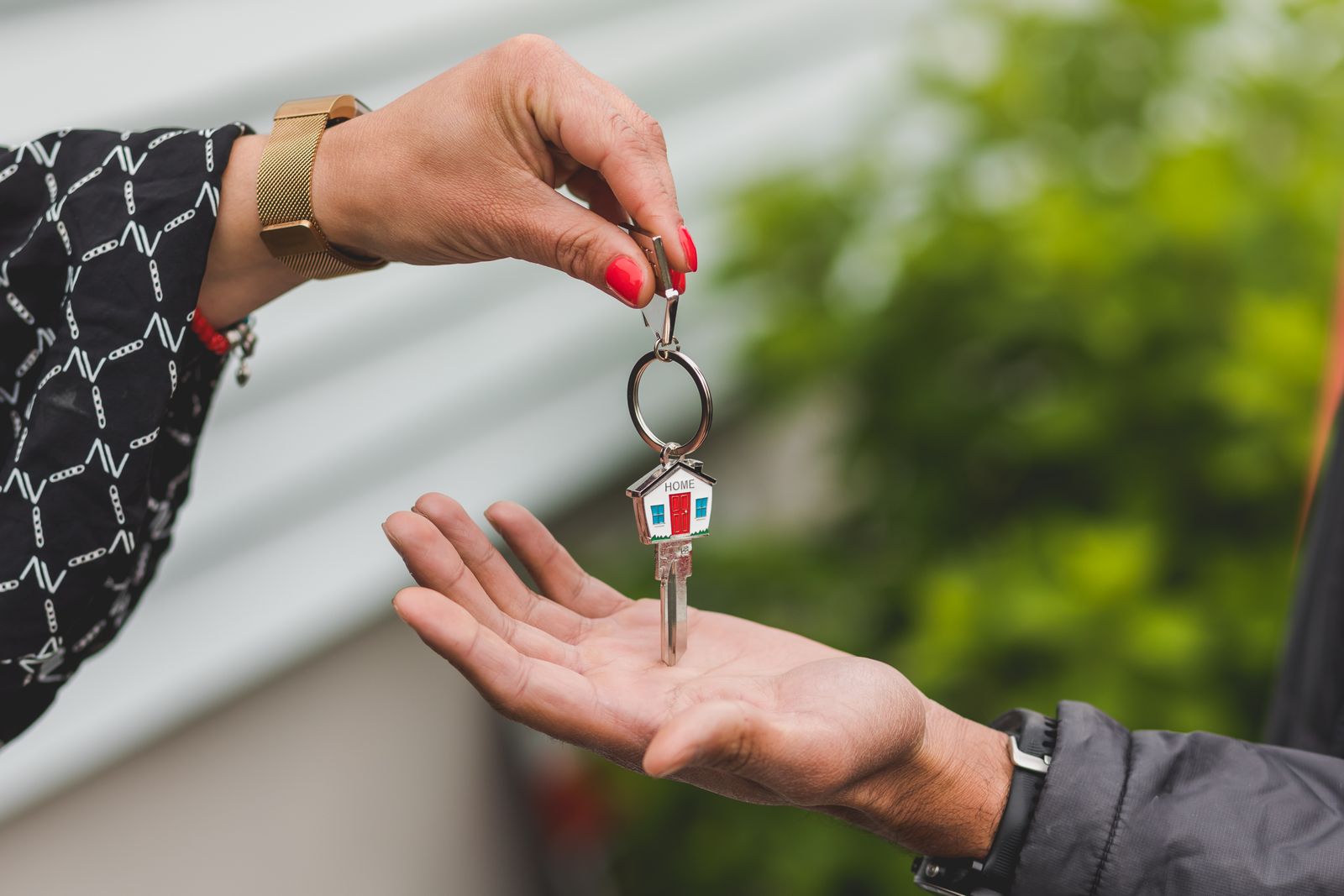 One person handing a house key on a keyring to another person's open hand