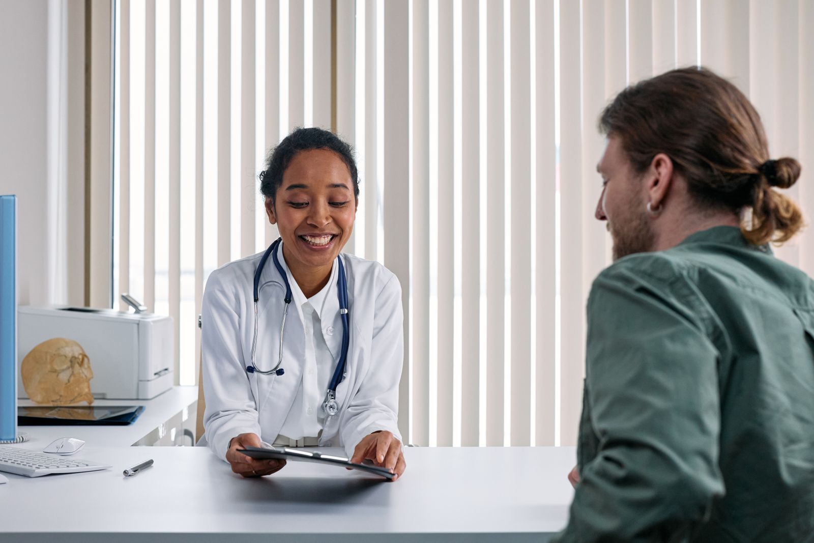 Doctor in a white coat going over a tablet with a patient across a clinic desk