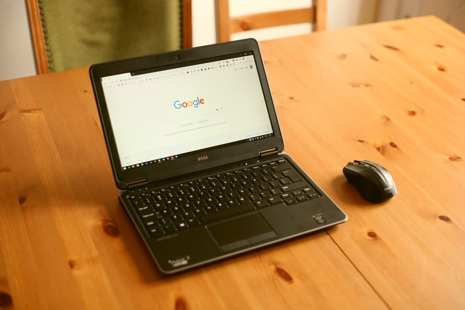 A laptop open on a wooden desk showing a search engine home page