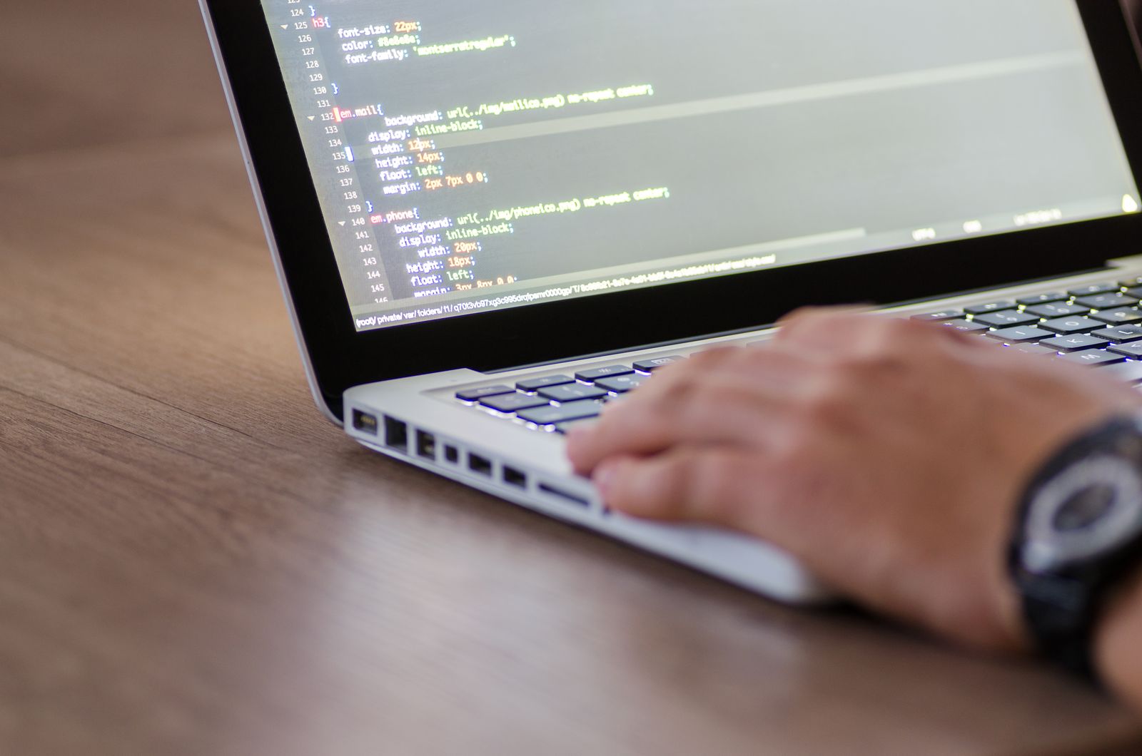 A developer editing CSS on a laptop, the layer Webflow abstracts and WordPress exposes