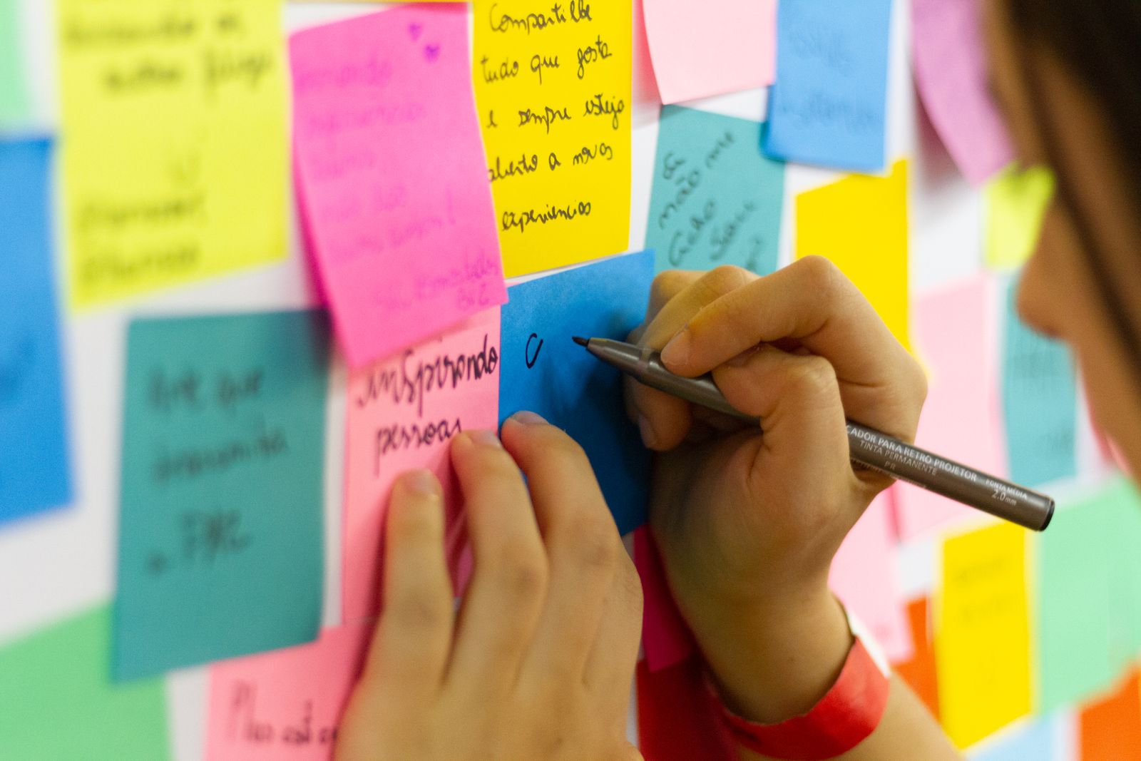 A person adding sticky notes to a wall covered in colorful options