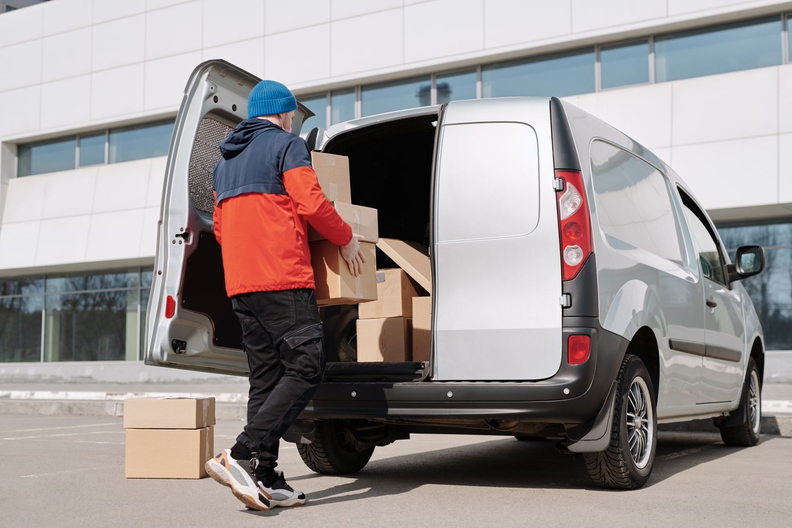 A person loading cardboard boxes into a van outside an office building